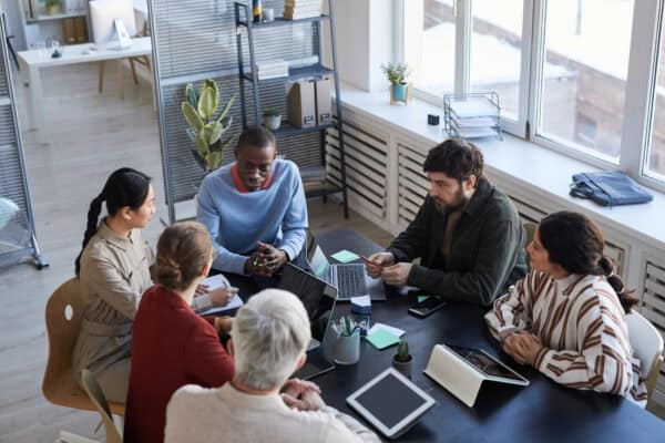 High angle view at diverse group of business people at table during briefing meeting in office, focus on smiling African-American man