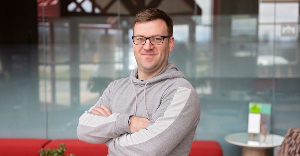 Man in gray hoodie standing with arms crossed