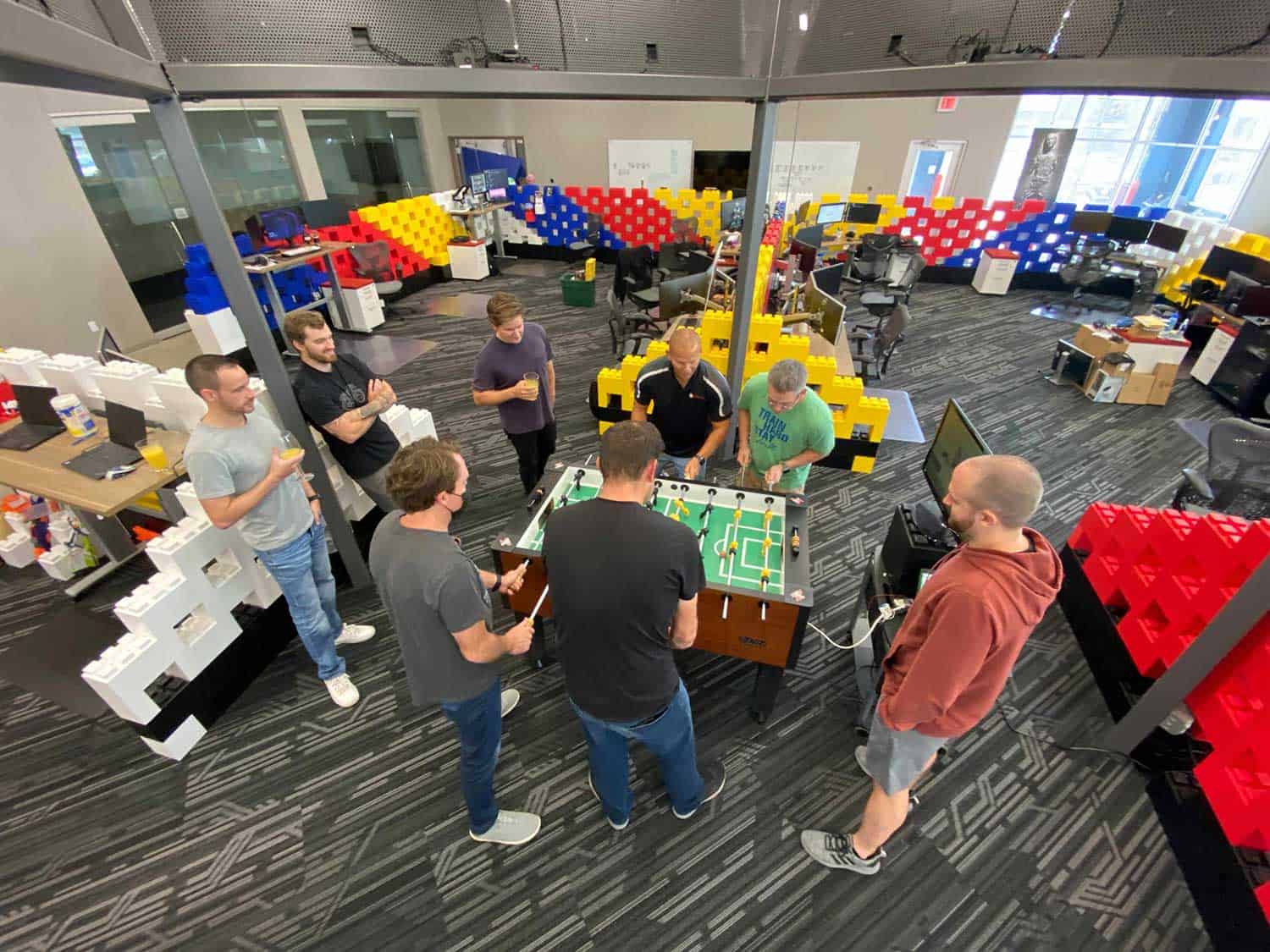 group of people standing around a foosball table
