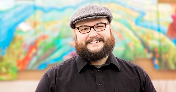 Man in black shirt standing in front of colorful art