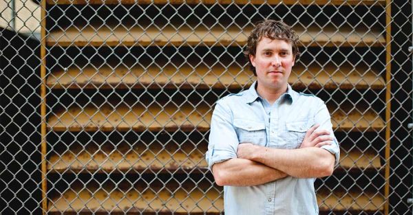 Cory VandenBout standing in front of chain-link fence