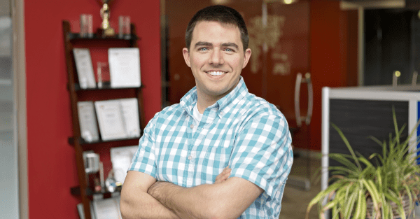 Man standing with arms crossed in a blue plaid shirt