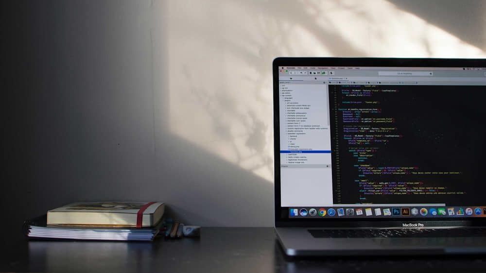 computer sitting on desk with book to the left