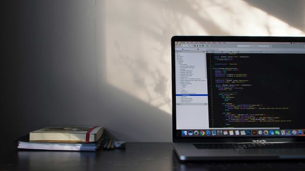 computer sitting on desk with book to the left