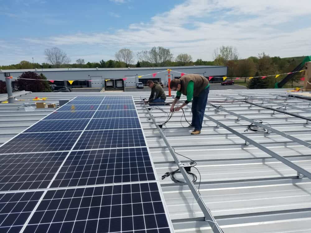Workers installing solar panels on BizStream's roof