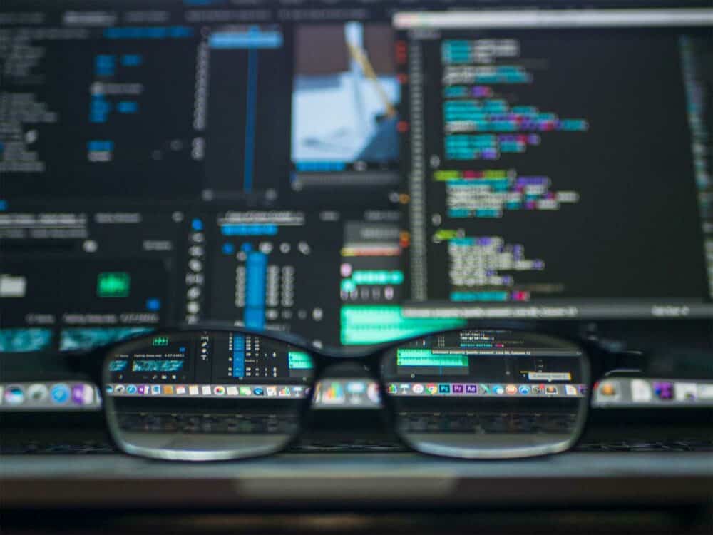 A pair of glasses sitting on a laptop displaying code