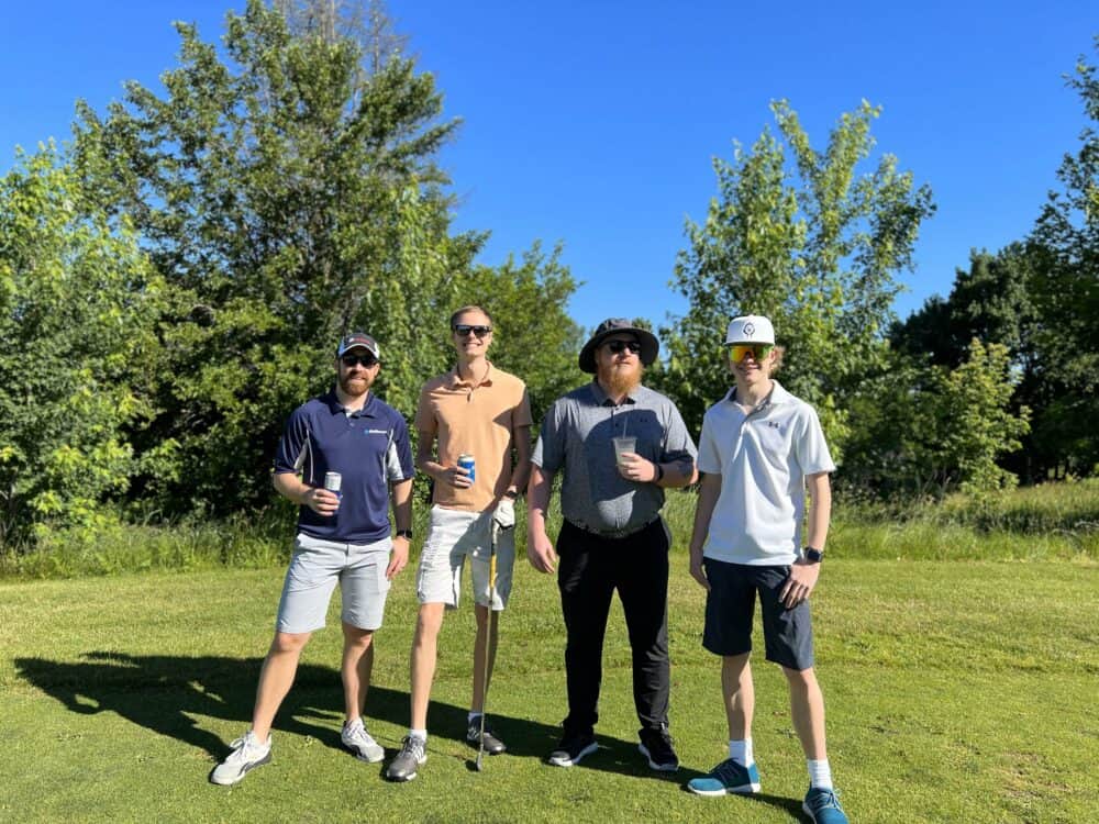 Four BizStream team members standing on a golf course.