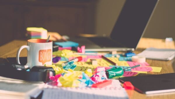 Crumpled Post-its on a desk with laptop and coffee mug