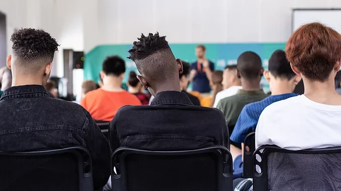 People sitting at a conference with their backs facing the camera
