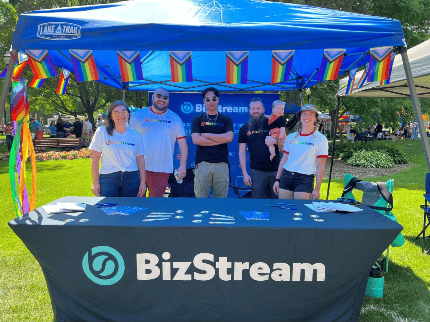 BizStream members standing behind a booth at Holland Pride festival.
