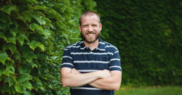 Man standing outside in a striped shirt with his arms crossed.