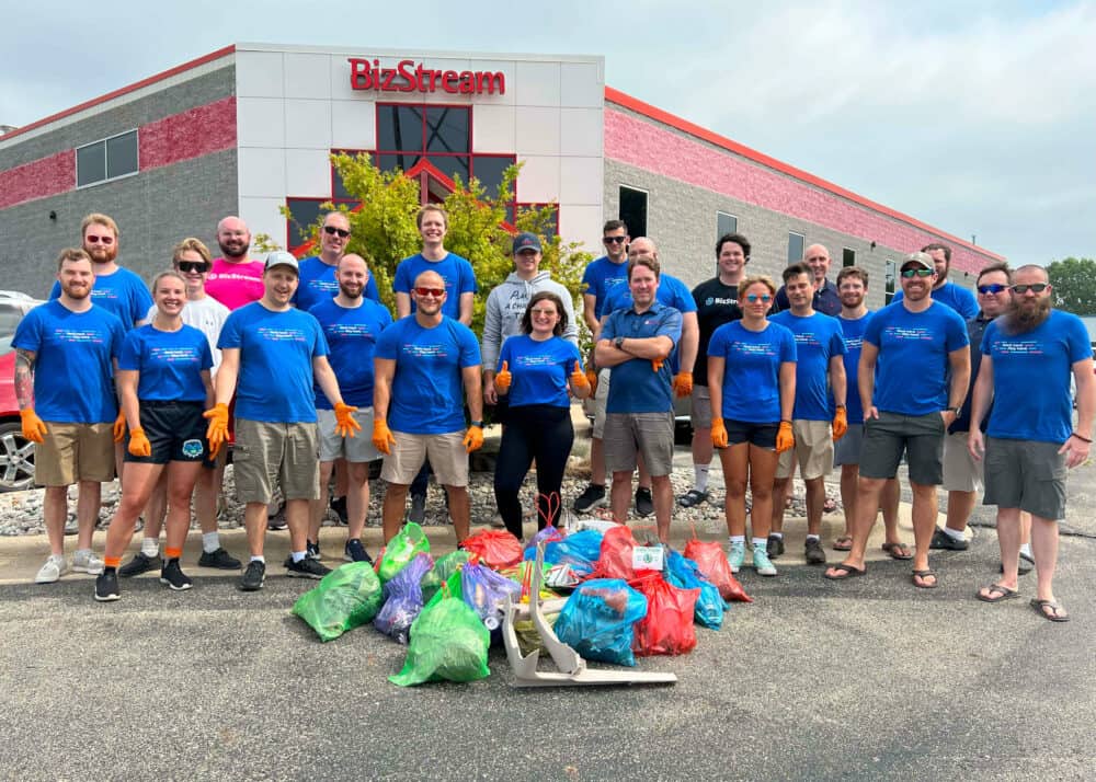 BizStream team members standing in front of the BizStream building with colorful bags of trash in front of them.