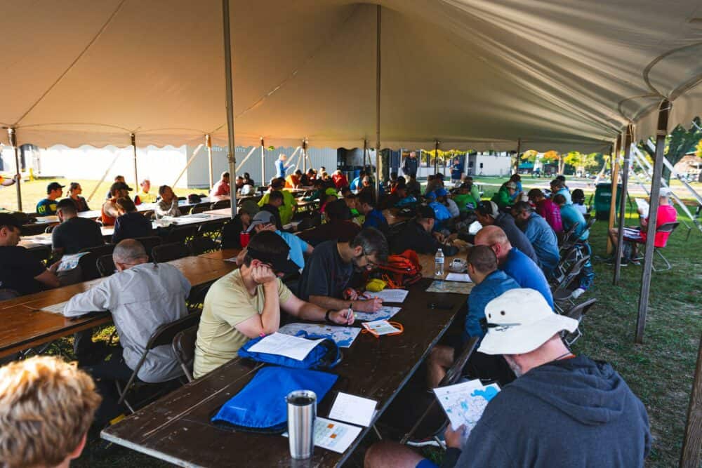 Group of people sitting at tables outside under a large tent