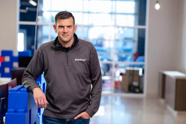 Man in gray shirt standing in front of a glass wall
