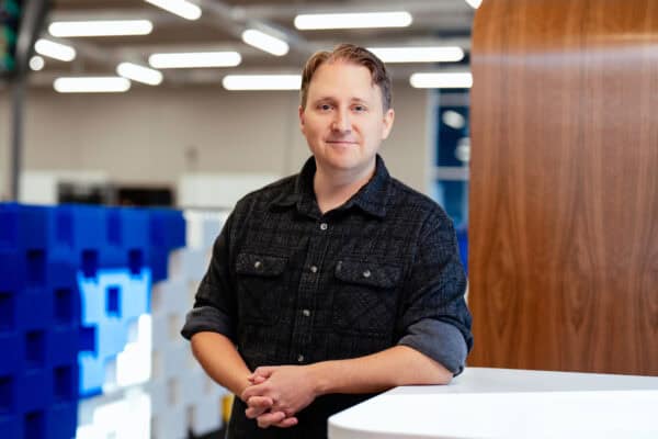 Man standing next to a table in front of a divider wall