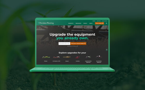 Precision Planting homepage on a laptop in front of a detailed photo of corn stalks growing.