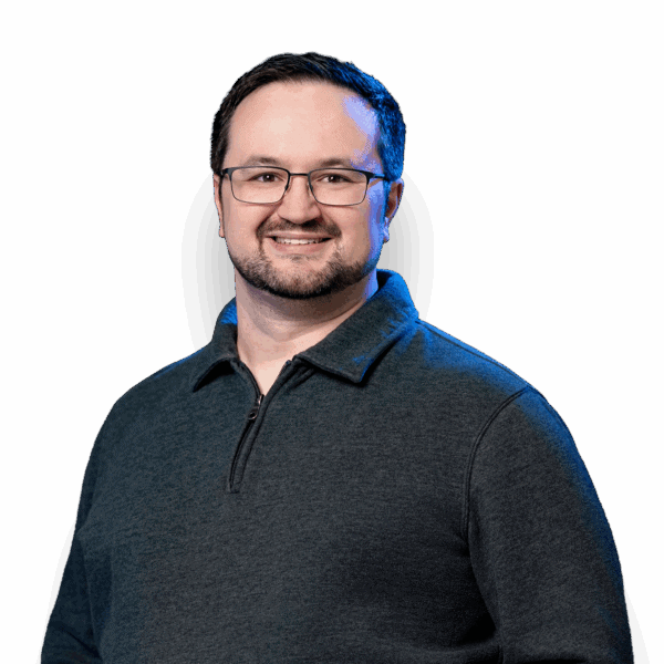 Kyle Dhyne smiling in glasses and a dark zip-up sweater.