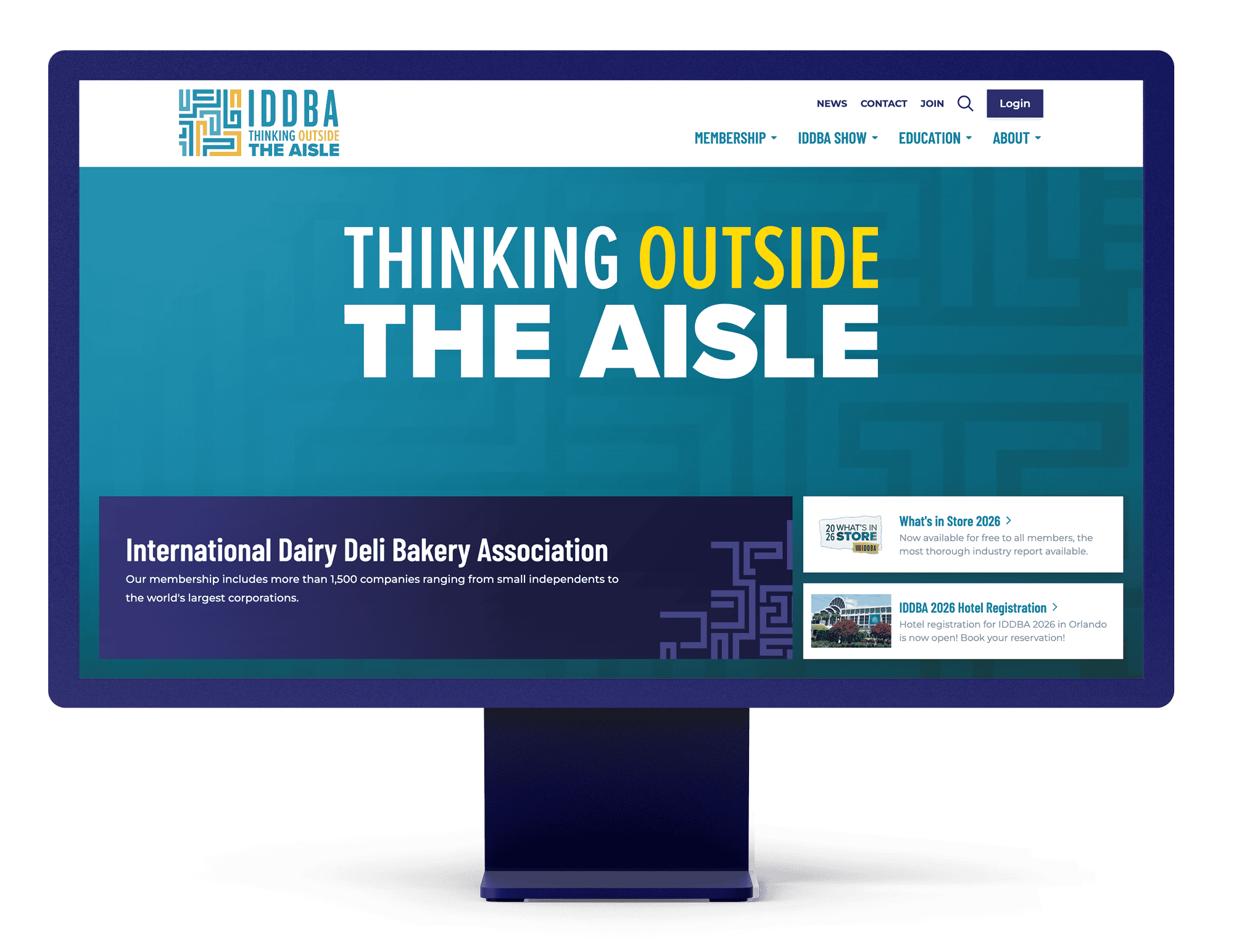 Desktop monitor displaying the IDDBA homepage with the headline “Thinking Outside the Aisle” and featured membership and event content.