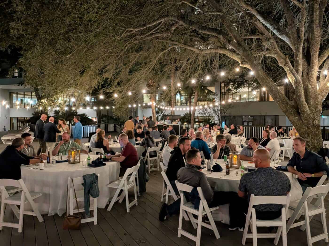 Kentico partners and clients gather for dinner under string lights and oak trees at Kentico Connection 2026 on Hilton Head Island.