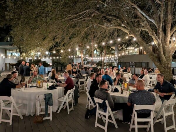 Kentico partners and clients gather for dinner under string lights and oak trees at Kentico Connection 2026 on Hilton Head Island.