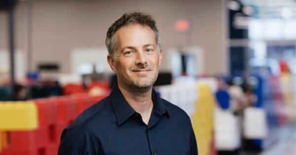 BizStream employee smiling in warehouse with colorful storage bins.