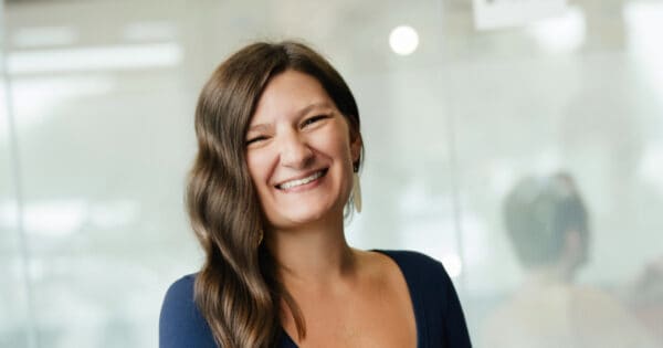 Happy woman with long brown hair smiling in office environment.