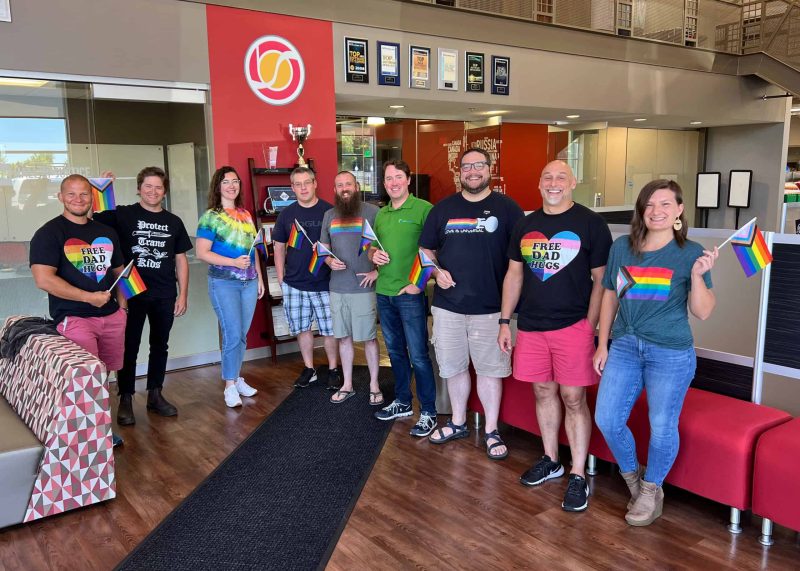 BizStream team members wearing LGBTQ+ shirts and holding flags
